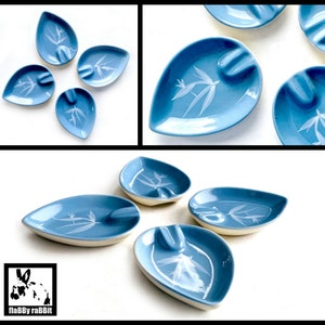 May include: Set of eight blue and white ceramic leaf-shaped ashtrays with a white floral design.