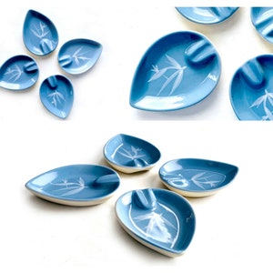 May include: A set of nine blue and white ceramic leaf-shaped ashtrays with a white bamboo design.