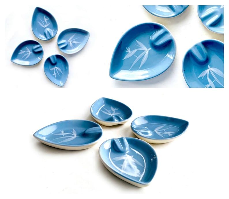May include: A set of nine blue and white ceramic leaf-shaped ashtrays with a white bamboo design.