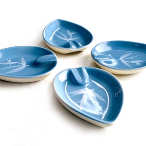 May include: Set of four blue ceramic leaf-shaped ashtrays with white floral designs.