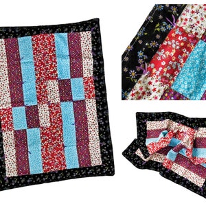 May include: A patchwork quilt with a black border and a variety of floral patterns in red, blue, and white. The quilt is folded in the center and the fabric is visible on the back.