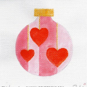 May include: A pink Christmas ornament with three red hearts hanging from it. The ornament has gold stripes and a gold top.