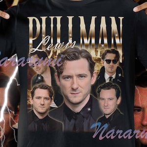 Puede incluir: Camiseta negra con el nombre "PULLMAN" en letras doradas e imágenes de Lewis Pullman. La camiseta tiene un estilo vintage, con el nombre "Lewis" en cursiva y un fondo de rayos.
