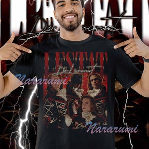 May include: Black t-shirt with a vintage design. The graphic features the text "L'ESTAT De Lioncourt" in red and gold, along with portraits of people in historical attire. The shirt also has the word "Nararumi" in a script font.