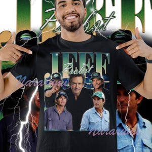 Peut inclure: T-shirt noir avec un collage d'images de Jeff Probst. Le t-shirt affiche le nom "Jeff Probst" dans une police dégradée verte et bleue. L'arrière-plan présente un motif vert et blanc avec des éclairs.