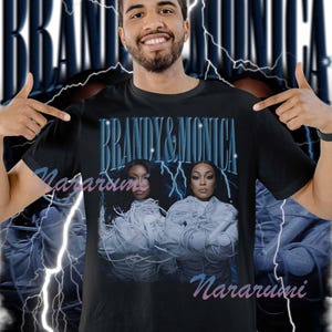 May include: Black t-shirt with the text "Brandy & Monica" in blue, and a vintage-style image of the singers. The design includes a lightning bolt graphic and the word "Nararumi" in a script font.