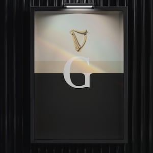 Minimalist art print inspired by Guinness branding, featuring a large letter G in black and cream tones, styled in a modern interior setting