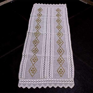 Può includere: Pannello di tenda in crochet bianco con un motivo a rombi e accenti dorati. La tenda ha un bordo a festoni.