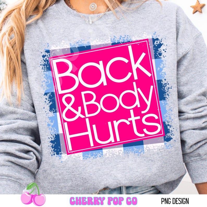May include: A gray sweatshirt with a pink square design that reads "Back & Body Hurts" in white text. The design is set against a blue and white plaid pattern with blue paint splatter accents. The bottom of the image has the text "CHERRY POP CO" and "PNG DESIGN".