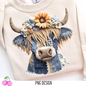 Może przedstawiać: Kremowa bluza z aplikacją przedstawiającą szkocką krowę. Krowa ma kwiatową koronę ze słonecznikiem i niebieskimi kwiatami. Projekt zawiera naszywki z dżinsu i szorstką grzywę. Tekst "PNG DESIGN" znajduje się na dole.
