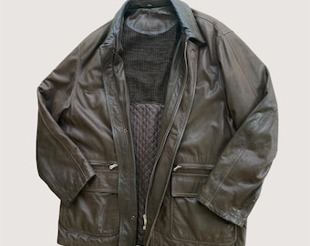 May include: A brown leather jacket with a collared neckline and multiple pockets. The jacket has a zip-up front and a quilted lining. The interior features a dark brown knit panel. The jacket is a classic outerwear piece.