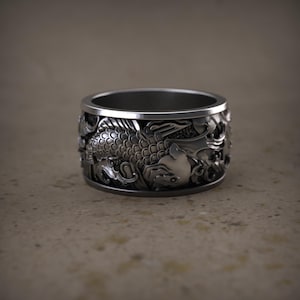 May include: A silver ring with a detailed design of two koi fish swimming in a wave pattern.