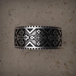 Peut inclure: Une bague argentée avec un motif détaillé de croix et de formes géométriques. La bague a un design à large bande avec une surface texturée. Le design complexe est répété autour de toute la bande, créant un accessoire audacieux et accrocheur.