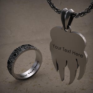 K&ouml;nnte beinhalten: Ein silberner Ring und eine Halskette mit Anh&auml;nger mit einem strukturierten Monddesign. Beide St&uuml;cke tragen den Text "Your Text Here" eingraviert.