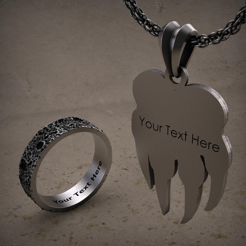 K&ouml;nnte beinhalten: Ein silberner Ring und eine Halskette mit Anh&auml;nger mit einem strukturierten Monddesign. Beide St&uuml;cke tragen den Text "Your Text Here" eingraviert.