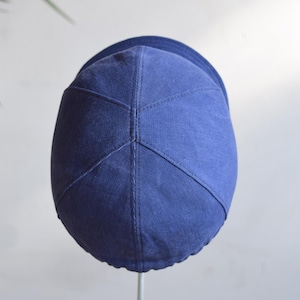 May include: A navy blue cap with a curved brim. The cap is made of a soft fabric and features a stitched design on the crown. The cap is a solid color and appears to be new.