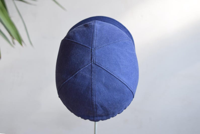 May include: A navy blue cap with a curved brim. The cap is made of a soft fabric and features a stitched design on the crown. The cap is a solid color and appears to be new.