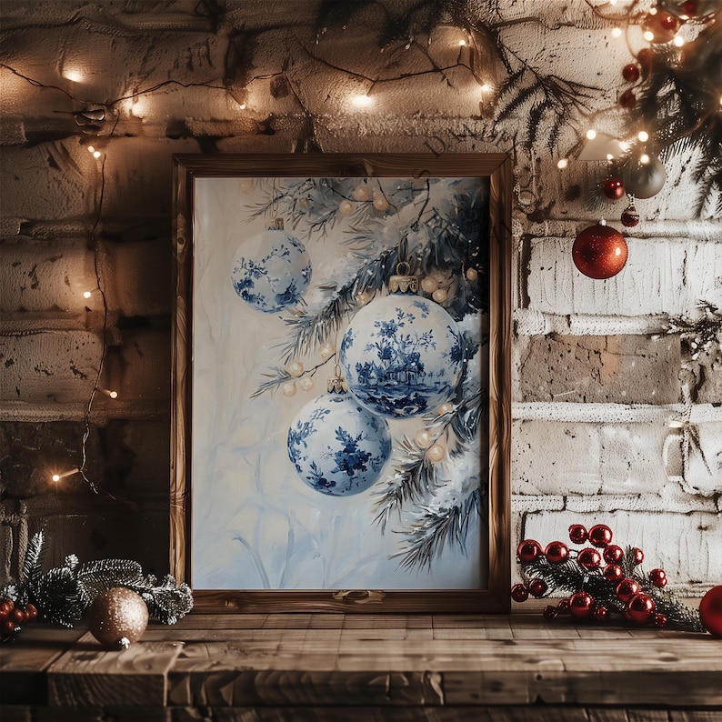May include: A framed print featuring blue and white Christmas ornaments with a floral design. The artwork is set against a light blue background with pine branches. The frame is made of dark wood, and the scene is set on a wooden surface.