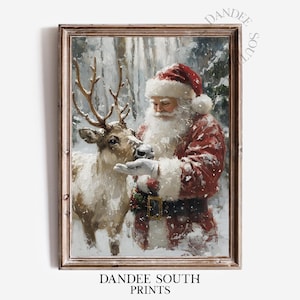 May include: Framed print of Santa Claus feeding a reindeer in a snowy forest. Santa wears a red suit and hat with a white beard. The reindeer has large antlers. The print is in a wooden frame. Text at the bottom reads "DANDEE SOUTH PRINTS".