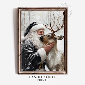 May include: A framed print featuring Santa Claus embracing a reindeer in a snowy forest. Santa, in a black and white suit with a white beard and hat, kisses the reindeer. The print has a brown wooden frame and the text "DANDEE SOUTH PRINTS".