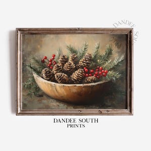 May include: A framed painting depicts a wooden bowl filled with pine cones, evergreen sprigs, and red berries. The artwork has a rustic, vintage aesthetic, with a warm color palette of browns, greens, and reds. The text "DANDEE SOUTH PRINTS" is at the bottom.