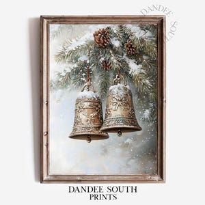 Pode incluir: Uma impressão emoldurada com dois sinos dourados ornamentados pendurados em um galho de pinheiro coberto de neve com pinhas. Os sinos têm intrincados desenhos florais e são polvilhados com neve. O texto "DANDEE SOUTH PRINTS" está na parte inferior.