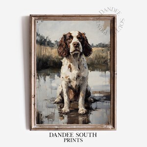 Peut inclure: Une impression encadrée d'un chien, peinte dans un style impressionniste. Le chien, un Springer Spaniel marron et blanc, est assis devant un plan d'eau. L'œuvre d'art a une esthétique vintage, avec le texte "DANDEE SOUTH PRINTS" en bas.