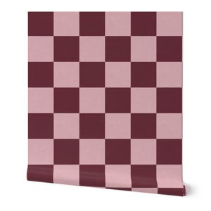 Puede incluir: Un rollo de papel pintado con un dise&ntilde;o de tablero de ajedrez. El dise&ntilde;o alterna cuadrados de color rosa apagado y borgo&ntilde;a oscuro. El rollo est&aacute; parcialmente desenrollado, revelando el patr&oacute;n y el borde del papel.