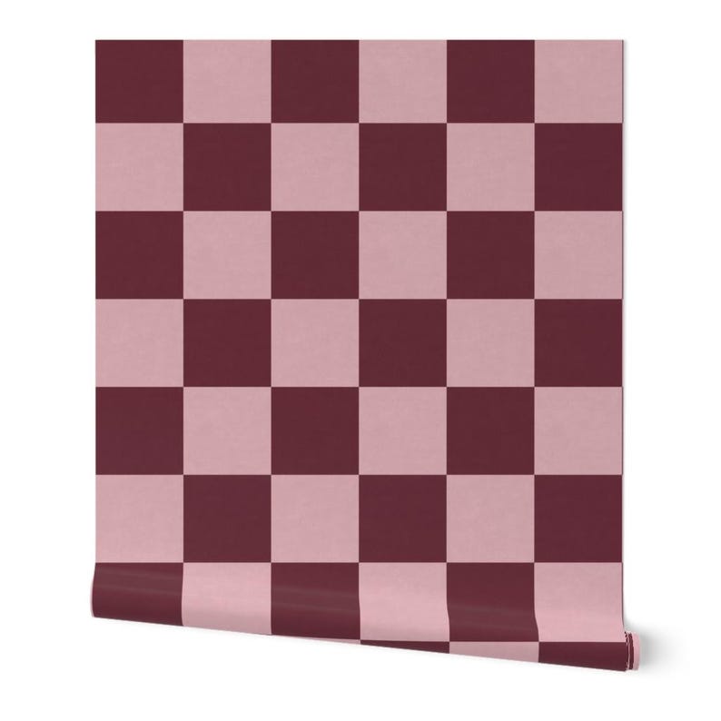 Puede incluir: Un rollo de papel pintado con un dise&ntilde;o de tablero de ajedrez. El dise&ntilde;o alterna cuadrados de color rosa apagado y borgo&ntilde;a oscuro. El rollo est&aacute; parcialmente desenrollado, revelando el patr&oacute;n y el borde del papel.