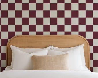May include: A bed with a white headboard and white bedding. The headboard is made of wood and has a rounded top. The wall behind the bed is covered in a checkerboard pattern wallpaper with burgundy and white squares.