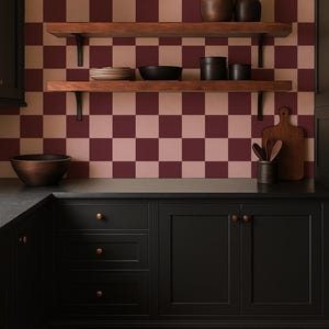 Puede incluir: Interior de cocina con pared a cuadros burdeos y beige. Estantes de madera con cer&aacute;mica y cuencos. Armarios negros con pomos de cobre y una tabla de cortar de madera. El suelo tiene un patr&oacute;n de espiga.