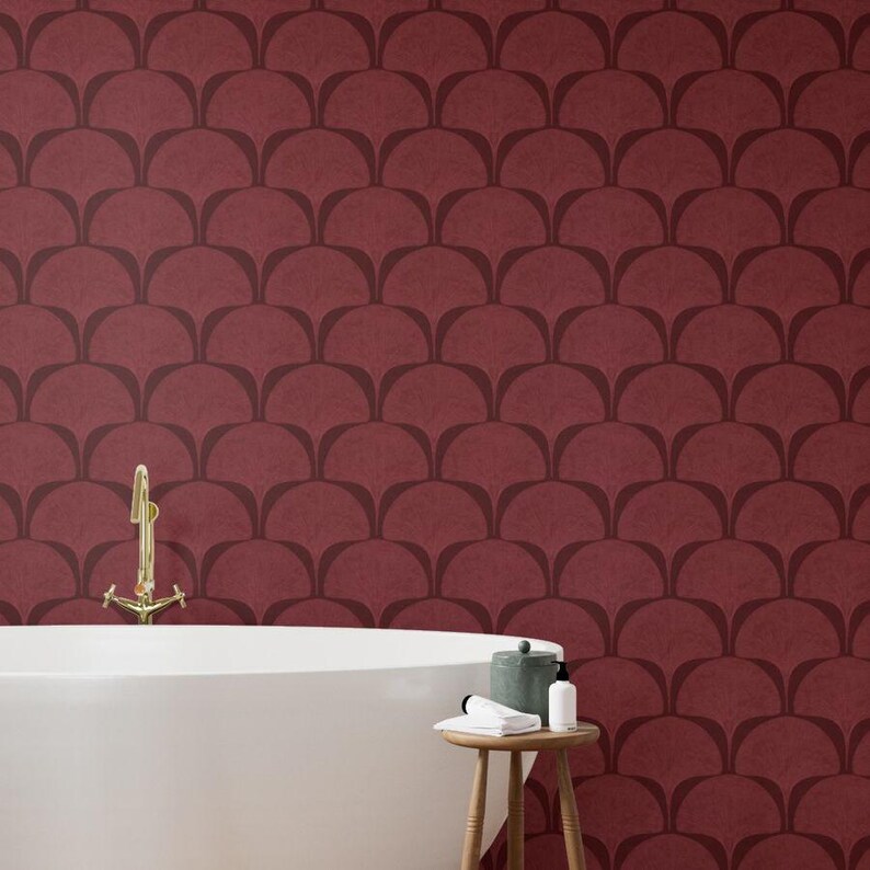 Pu&ograve; includere: Un bagno con una parete bordeaux con un motivo ripetuto a forma di ventaglio marrone scuro. Una vasca da bagno bianca e uno sgabello in legno con articoli da toeletta sono in primo piano. Un rubinetto dorato &egrave; montato a parete.