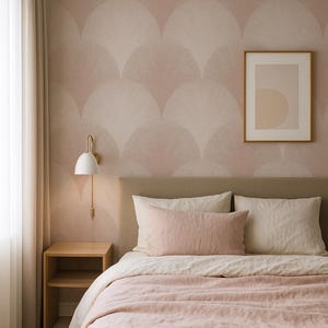 May include: A bedroom featuring a bed with a light pink linen duvet and matching rectangular pillow, a beige upholstered headboard, a light wood nightstand, a white wall sconce, and wallpaper with a repeating pale pink fan-shaped pattern.