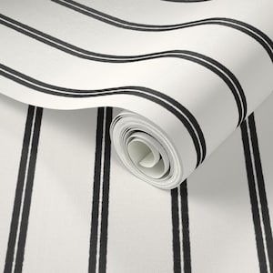 May include: A roll of wallpaper featuring a repeating pattern of black vertical stripes and curved black lines on a white background. The wallpaper is partially unrolled, revealing the rolled-up portion.