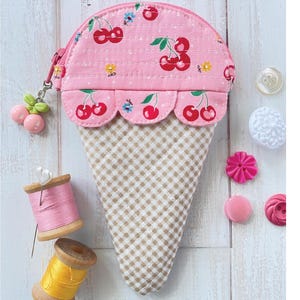 Könnte beinhalten: Ein rosa Eiswaffel-förmiges Täschchen mit Kirschmuster und einem Vichy-Karo-Kegel. Das Täschchen hat einen Reißverschluss und einen Kirsch-Anhänger. Der Text "Charise Creates Sewing Patterns" steht oben. Fertige Größe: Klein - 16.5 cm hoch.