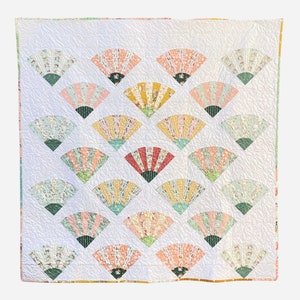 May include: A white quilt featuring a pattern of colourful fans. The fans are made from different fabrics and are arranged in a symmetrical design. The quilt is quilted with white thread.