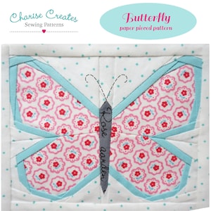 May include: A quilted butterfly design with a pink floral pattern on the wings, outlined in light blue. The butterfly's body is gray with the words "Rose garden" vertically. The background is white with small blue polka dots. The text "Butterfly paper pieced pattern" is in a light blue oval.