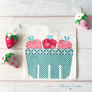 May include: A white fabric square with a green and white checked basket filled with three pink and white fabric strawberries. The strawberries have white stems and green leaves. The fabric square has the text "Charisse Creates" in the bottom right corner.