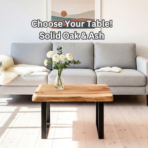 Può includere: Un tavolino rettangolare con un piano in legno massello a bordo naturale e due gambe in metallo nero a forma di U. È presente il testo Choose Your Table! Solid Oak & Ash. Un vaso di vetro trasparente con fiori bianchi poggia sul piano.