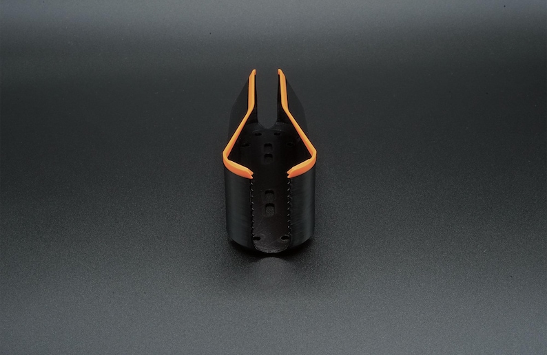 May include: A black and orange bottle holder. The holder is cylindrical with an open top and a curved orange trim. The holder has a series of small holes and is set against a dark background.