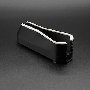 May include: A black, rectangular object with a white, curved top and interior. The object is set against a dark gray background. The design is modern and minimalist.