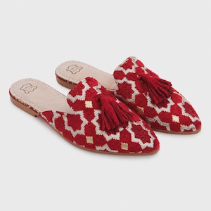May include: A pair of red and gold patterned slip-on shoes with a pointed toe and a small tassel. The shoes have a geometric design and a leather insole. The shoes are a size 8.