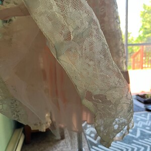 May include: A white lace overlay with a delicate floral pattern. The lace is sheer and has a soft, flowing texture.