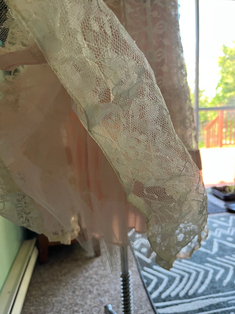 May include: A white lace overlay with a delicate floral pattern. The lace is sheer and has a soft, flowing texture.