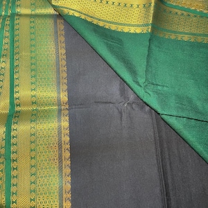 May include: A black and green saree with a gold border. The saree is made of a soft, silky fabric and has a traditional Indian design.