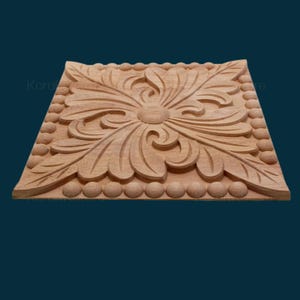 May include: A square wooden plaque with a carved floral design. The plaque has a raised border of small round beads.