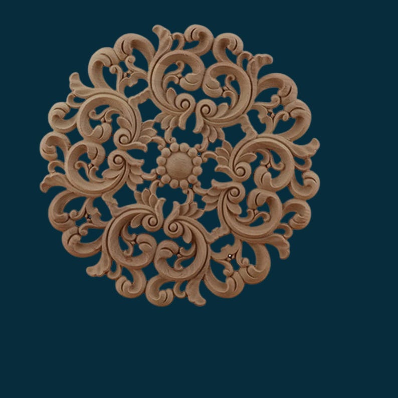 May include: A round, wooden decorative wall plaque with a carved, intricate floral design. The plaque is painted in a light brown colour and features a central circular motif.