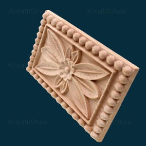 May include: A rectangular, unfinished wooden decorative element with a carved floral design. The central flower is surrounded by detailed leaves. The border features a series of small, rounded beads. The text "KcraftKStore" is visible in the corners.