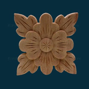 May include: A wooden carved flower design with four petals and a centre carved with a starburst pattern. The flower is a light brown colour.