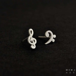 May include: A pair of silver earrings featuring a treble clef and a bass clef.